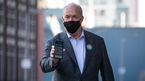 B.C. Premier John Horgan shows his provincial COVID-19 vaccine card as he arrives for a National Day for Truth and Reconciliation announcement with the B.C. Lions, in Vancouver, on Thursday, September 16, 2021. THE CANADIAN PRESS/Darryl Dyck 