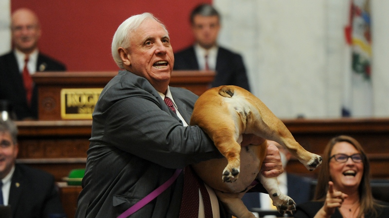 West Virginia Gov. Jim Justice holds up his dog Babydog's rear end as a message to people who've doubted the state as he comes to the end of his State of the State speech in the House chambers, Thursday, Jan. 27, 2022, in Charleston, W.Va. (Chris Dorst/Charleston Gazette-Mail via AP)