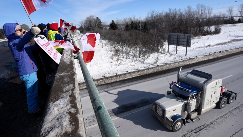 People wave flags as a truck participating in a cross-country convoy protesting a federal vaccine mandate for truckers, makes its way along Highway 416 in Ottawa, Friday, Jan. 28, 2022. THE CANADIAN PRESS/Justin Tang 