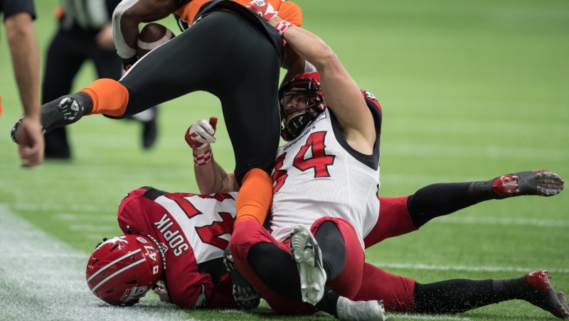 B.C. Lions' James Butler, front left, is tackled by Calgary Stampeders' Ante Milanovic-Litre (34) and Fraser Sopik (47) during the first half of a CFL football game in Vancouver, on Friday, November 12, 2021. (THE CANADIAN PRESS/Darryl Dyck) 