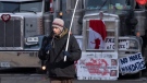 A man blows on a horn as he walks past trucks parked in the downtown core on Tuesday, Feb. 1, 2022 in Ottawa. (THE CANADIAN PRESS/Adrian Wyld)