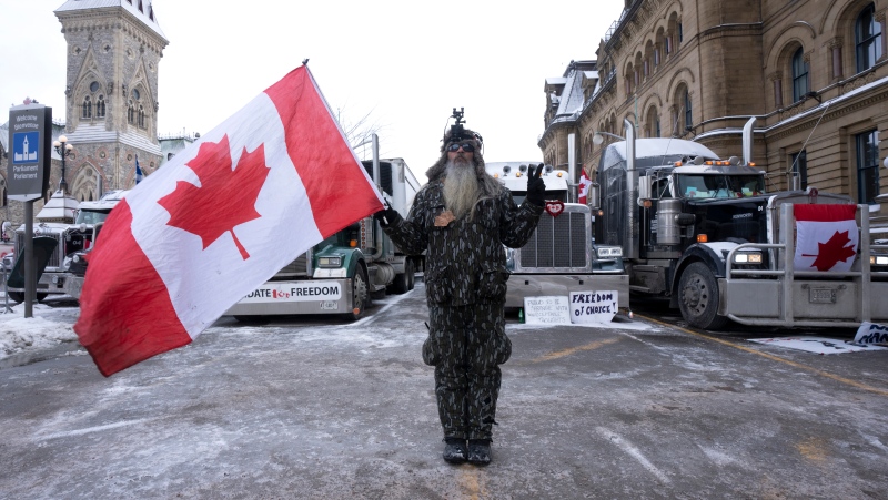 A protester stands in front of vehicles parked in the downtown core, Thursday, Feb. 3, 2022 in Ottawa. (Adrian Wyld/THE CANADIAN PRESS)
