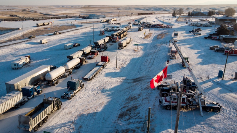 A truck convoy protesting COVID-19 vaccine mandates blocks the highway at the busy U.S. border crossing in Coutts, Alta., on Feb. 2, 2022. THE CANADIAN PRESS/Jeff McIntosh