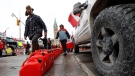 People walk past fuel cans in front of Parliament Hill as a rally against COVID-19 restrictions, which began as a cross-country convoy protesting a federal vaccine mandate for truckers, continues in Ottawa, on Wednesday, February 9, 2022. (Patrick Doyle/THE CANADIAN PRESS)