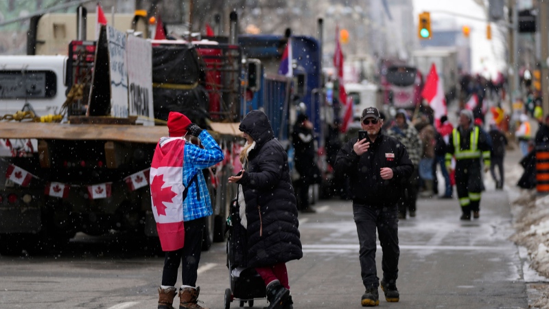 Light snow begins to fall as protesters converse in the street on the 15th day of a protest against COVID-19 restrictions that has grown into a broader anti-government protest, in Ottawa, on Friday, Feb. 11, 2022. THE CANADIAN PRESS/Justin Tang