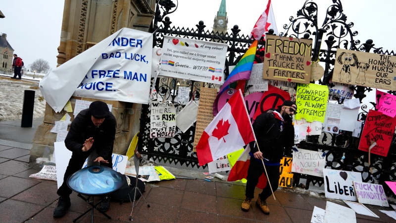 Protesters drum, dance and smoke in front of the Queen’s Gates on Parliament Hill, on the 15th day of a protest against COVID-19 measures that has grown into a broader anti-government protest, in Ottawa, Friday, Feb. 11, 2022. 
(Justin Tang/THE CANADIAN PRESS)
