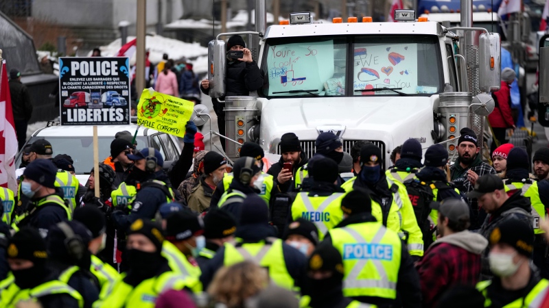 A protester records police as they form a ring around protesters who were building a tent structure on Wellington Street, on the 15th day of a protest against COVID-19 measures that has grown into a broader anti-government protest, in Ottawa, Friday, Feb. 11, 2022. 
(Justin Tang/THE CANADIAN PRESS)
