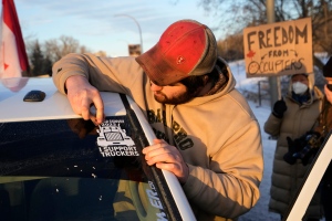 A convoy participant removes a windshield sticker