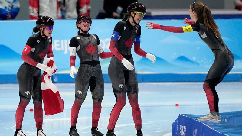 Alexa Scott, right, reaches out to Isabelle Weidemann, centre, Ivanie Blondin and Valerie Maltais after they won the gold medal and set an Olympic record in the speedskating women's team pursuit finals at the 2022 Winter Olympics in Beijing. (AP Photo/Ashley Landis)