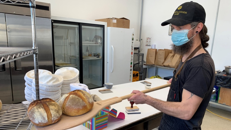 Roland Jensch takes sourdough bread out of the oven at Grains and Goods Bakery in Sydenham, Ont. (Kimberley Johnson/CTV News Ottawa)