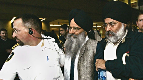 Ripudaman Singh Malik is flanked by a sherriff, left, and an unidentified man, right, as he is escorted to a waiting car outside B.C. Supreme Court in Vancouver Wednesday March 16, 2005, after being found not guilty in the bombing of Air India flight 182 in 1985. (CP PHOTO/Chuck Stoody)