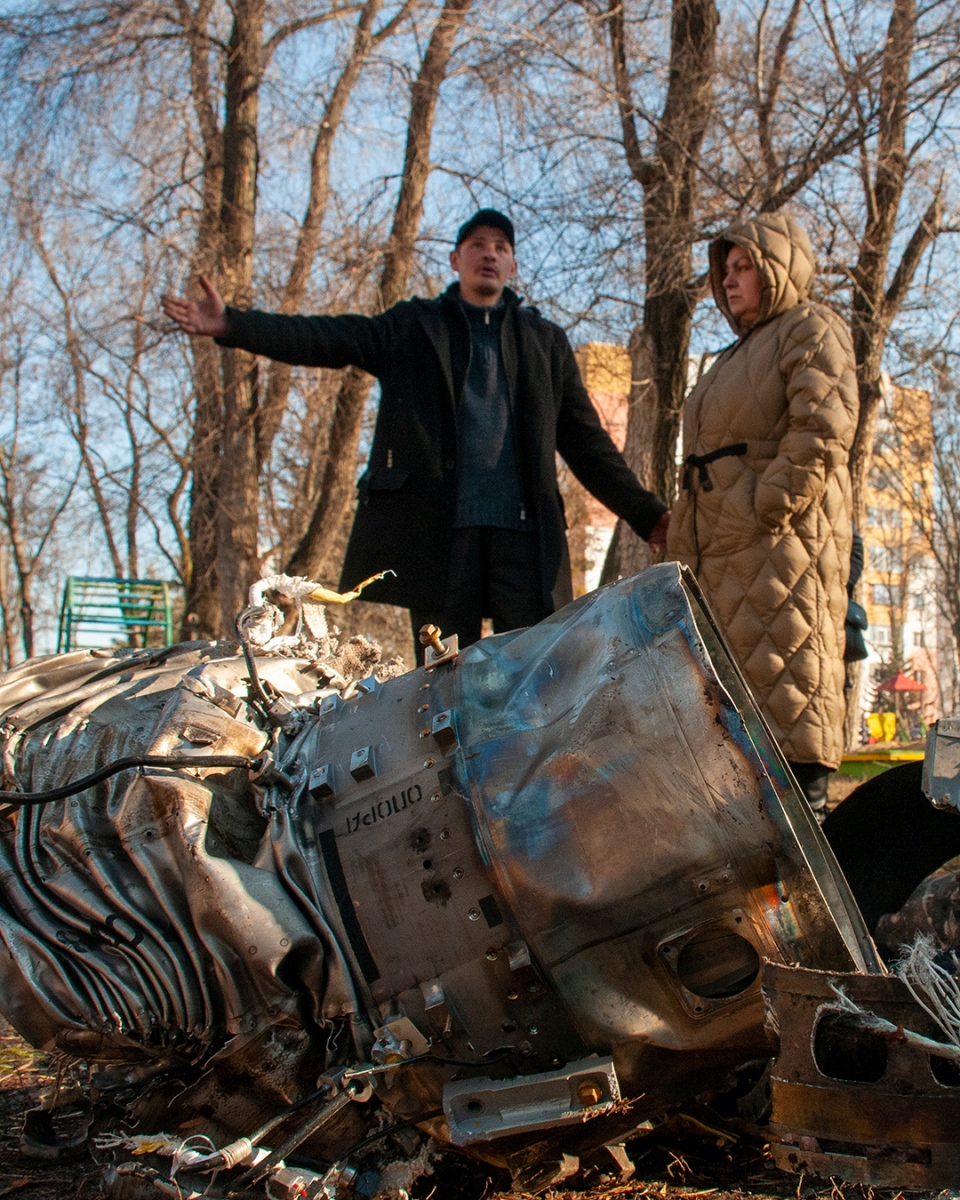 People stand next to debris in Kharkiv