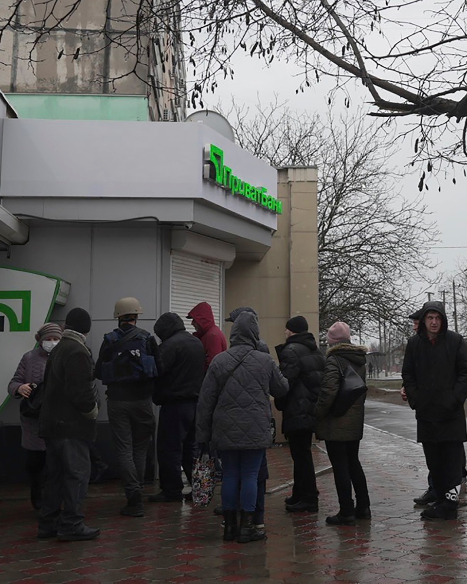 People line up to withdraw their money from an ATM