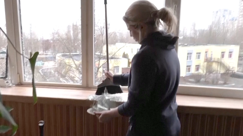 Kyiv woman picks up broken glass, sings anthem