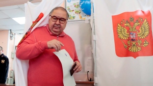 Russian businessman Alisher Usmanov exits a polling booth as he prepares to cast his ballot a at the presidential election in Moscow, Sunday, March 18, 2018. Russians are voting in a presidential election in which Vladimir Putin is seeking a fourth term in the Kremlin. (AP Photo/Denis Tyrin)