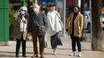 An elderly couple wearing masks wait to cross Ossington St. next to two unmasked younger women, Toronto, Thursday, October 28, 2021. The Ontario government has lifted restrictions on outdoor gathering starting today. THE CANADIAN PRESS/Eduardo Lima