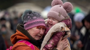 A woman holding a child cries after fleeing from the Ukraine and arriving at the border crossing in Medyka, Poland, Monday, March 7, 2022. (AP Photo/Visar Kryeziu)