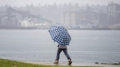A pedestrian uses an umbrella to shield against the heavy rain as they walk along the shore of the harbour in Vancouver Tuesday, January 11, 2022. THE CANADIAN PRESS/Jonathan Hayward