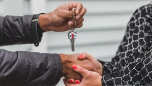 Two people are seen shaking hands and exchanging the key to a home in this stock photo. (RODNAE Productions / Pexels.com)