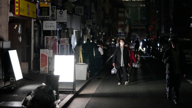 People walk on a street during a black out in Tokyo Thursday, March 17, 2022, following an earthquake. (Kyodo News via AP)