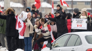 Protesters cheer at cars as they stand on a street corner outside the restricted area in the downtown core, in Ottawa, Sunday, Feb. 20, 2022. THE CANADIAN PRESS/Adrian Wyld 