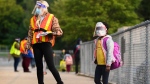 Five year-old Nancy Murphy wears a full mask and face shield as she waits in line for her kindergarten class to enter the school at Portage Trail Community School which is part of the Toronto District School Board (TDSB) during the COVID-19 pandemic in Toronto on Tuesday, September 15, 2020. THE CANADIAN PRESS/Nathan Denette 