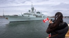 A woman takes a photo as HMCS Halifax departs Halifax in support of NATO's deterrence measures in eastern Europe on Saturday, March 19, 2022. THE CANADIAN PRESS/Andrew Vaughan
