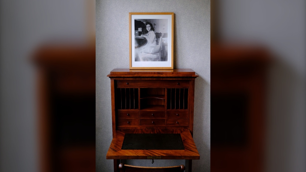A photo of Anne Frank on a replica of her desk