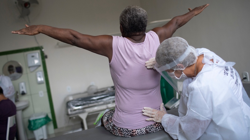 Therapist Monica Cirne gives physical therapy to COVID-19 survivor Maria dos Santos at the Movement and Life Institute in Rio de Janeiro, Brazil on Nov. 9, 2020. (AP Photo/Silvia Izquierdo)