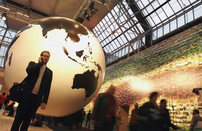 A man speaks on his cell phone in front of a giant globe in the main venue hall of the UN Climate Summit in Copenhagen, Tuesday, Dec. 15, 2009. (AP / Virginia Mayo)