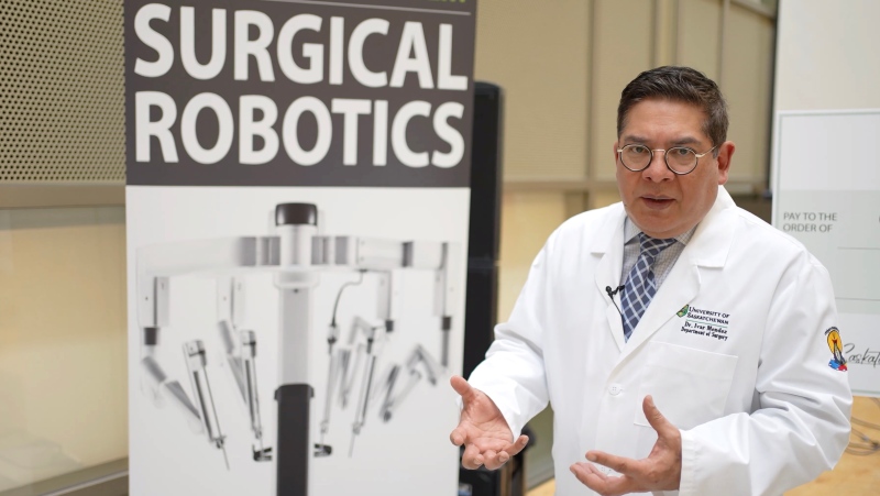 Dr. Ivar Mendez beside a picture of the surgical robot, which arrived earlier this year. (Laura Woodward/CTV News)