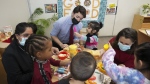 FILE- Canadian Prime Minister Justin Trudeau, back centre, plays with children in a daycare centre after reaching an agreement on $10-a-day child-care with Ontario Premier Doug Ford, not pictured, in Brampton, Ont., Monday, March 28, 2022. Feminist advocates say the budget doesn't fully account for the challenges in scaling up child-care systems across the country. THE CANADIAN PRESS/Nathan Denette