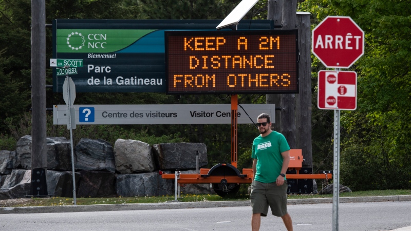 A sign advises people to practice physical distancing as they enter Gatineau Park in Chelsea, Que., on Sunday, May 24, 2020, in the midst of the COVID-19 pandemic. (Justin Tang/THE CANADIAN PRESS)