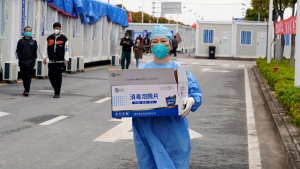 In this photo released by China's Xinhua News Agency, a worker carries a box of supplies at a makeshift hospital in Shanghai, China, April 15, 2022. (Yang Youzong/Xinhua via AP)