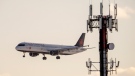 An Air Canada jet flies past a cell phone tower as it comes in to land at Pearson Airport in Toronto on Thursday January 20, 2022. (THE CANADIAN PRESS/Frank Gunn)