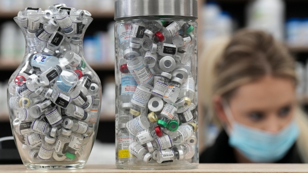 Jars full of empty COVID-19 vaccine vials are shown as a pharmacist works behind the counter at the Junction Chemist pharmacy during the COVID-19 pandemic in Toronto on Wednesday, April 6, 2022. THE CANADIAN PRESS/Nathan Denette