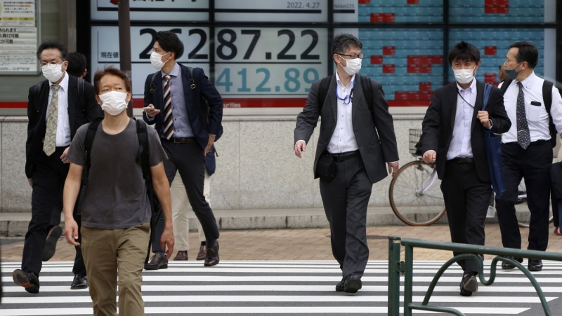 People walk by an electronic stock board of a securities firm in Tokyo, April 27, 2022. (AP Photo/Koji Sasahara)