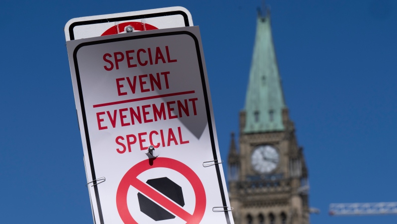 A temporary no-stopping sign is fixed with paper clips to a road sign near Parliament Hill, Thursday, April 28, 2022 in Ottawa. The area is part of a motorized vehicle exclusion zone set by the Ottawa Police Service. (Adrian Wyld/THE CANADIAN PRESS)