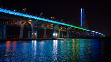 FILE: The Samuel de Champlain Bridge is lit to the colours of the rainbow in solidarity to healthcare workers in Montreal, on Monday, April 6, 2020. THE CANADIAN PRESS/Paul Chiasson