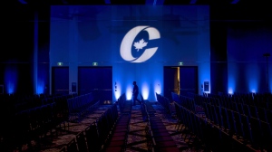 A man is silhouetted walking past a Conservative Party logo before the opening of the Party's national convention in Halifax on August 23, 2018. THE CANADIAN PRESS/Darren Calabrese