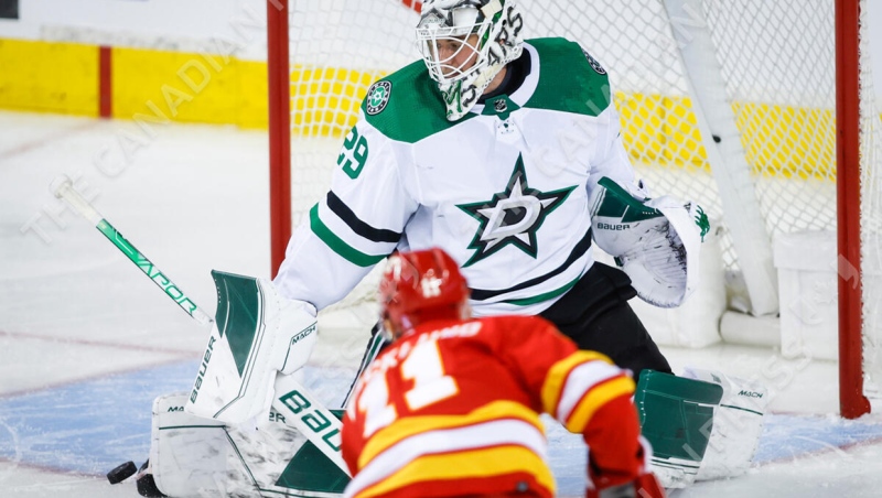 Dallas Stars goalie Jake Oettinger, right, kicks a away a shot from Calgary Flames centre Mikael Backlund during second period NHL playoff hockey action in Calgary, Thursday, May 5, 2022.THE CANADIAN PRESS/Jeff McIntosh