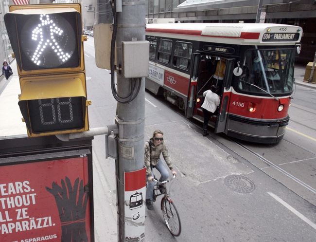 A TTC streetcar takes on passengers as a cyclist rolls past a pedestrian walk sign in downtown Toronto, Sunday, April 20, 2008. (J.P. Moczulski / THE CANADIAN PRESS)  