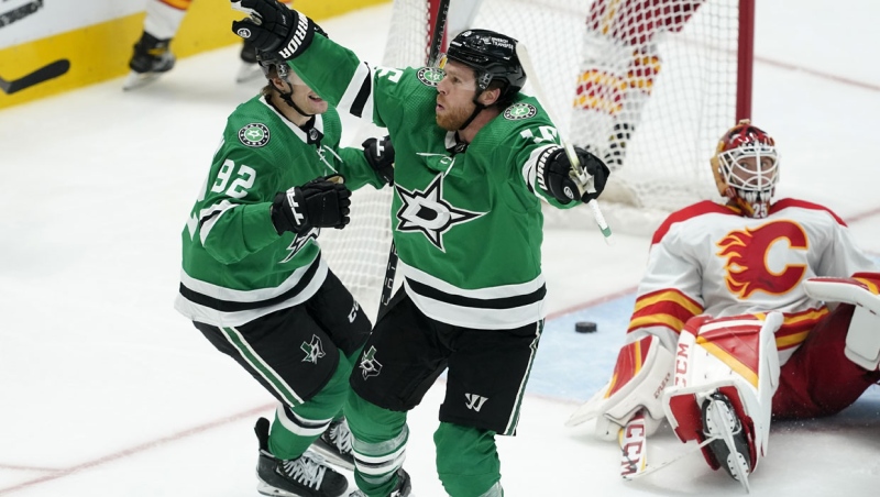 Dallas Stars center Joe Pavelski (16) and Vladislav Namestnikov (92) celebrate after Pavelski scored against Calgary Flames goaltender Jacob Markstrom, right, the third period of Game 3 of an NHL hockey Stanley Cup first-round playoff series, Saturday, May 7, 2022, in Dallas. The Stars won 4-2. (AP Photo/Tony Gutierrez)
