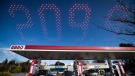 In this double exposure photograph, a sign displays the price of a litre of regular grade gasoline as people fuel up their vehicles at an Esso gas station, in Vancouver, on Tuesday, March 8, 2022. THE CANADIAN PRESS/Darryl Dyck 