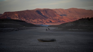 A formerly sunken boat sits on cracked earth hundreds of feet from what is now the shoreline on Lake Mead at the Lake Mead National Recreation Area, Monday, May 9, 2022, near Boulder City, Nev. (AP Photo/John Locher)