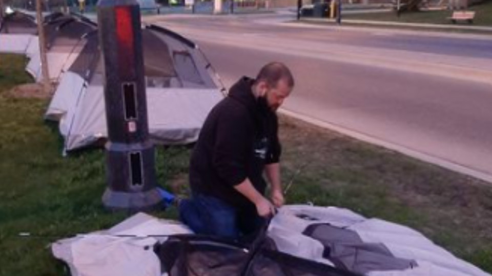 Shelter supporter sets up tent on Lakeshore