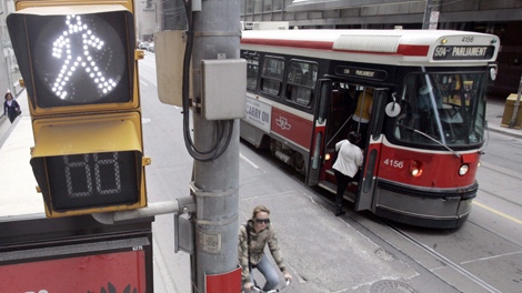 A TTC streetcar takes on passengers as a cyclist rolls past a pedestrian walk sign in downtown Toronto, Sunday, April 20, 2008. (J.P. Moczulski / THE CANADIAN PRESS)  