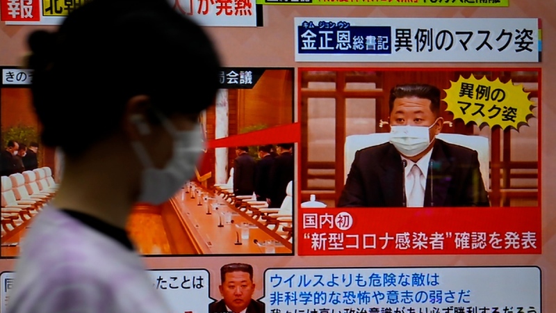 A passerby walks past a screen displaying an image of North Korean leader Kim Jong Un wearing a face mask on a TV news program in Tokyo, Japan, on May 13, 2022.  (Shuji Kajiyama / AP) 