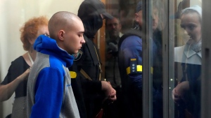 Russian army Sgt. Vadim Shyshimarin, 21, is seen behind a glass during a court hearing in Kyiv, Ukraine, Friday, May 13, 2022. The trial of a Russian soldier accused of killing a Ukrainian civilian opened Friday, the first war crimes trial since Moscow's invasion of its neighbor. (AP Photo/Efrem Lukatsky)
