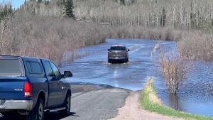 Vehicles travel down a flooded road in Kenora on May 13, 2022 (CTV News Photo Scott Andersson)
